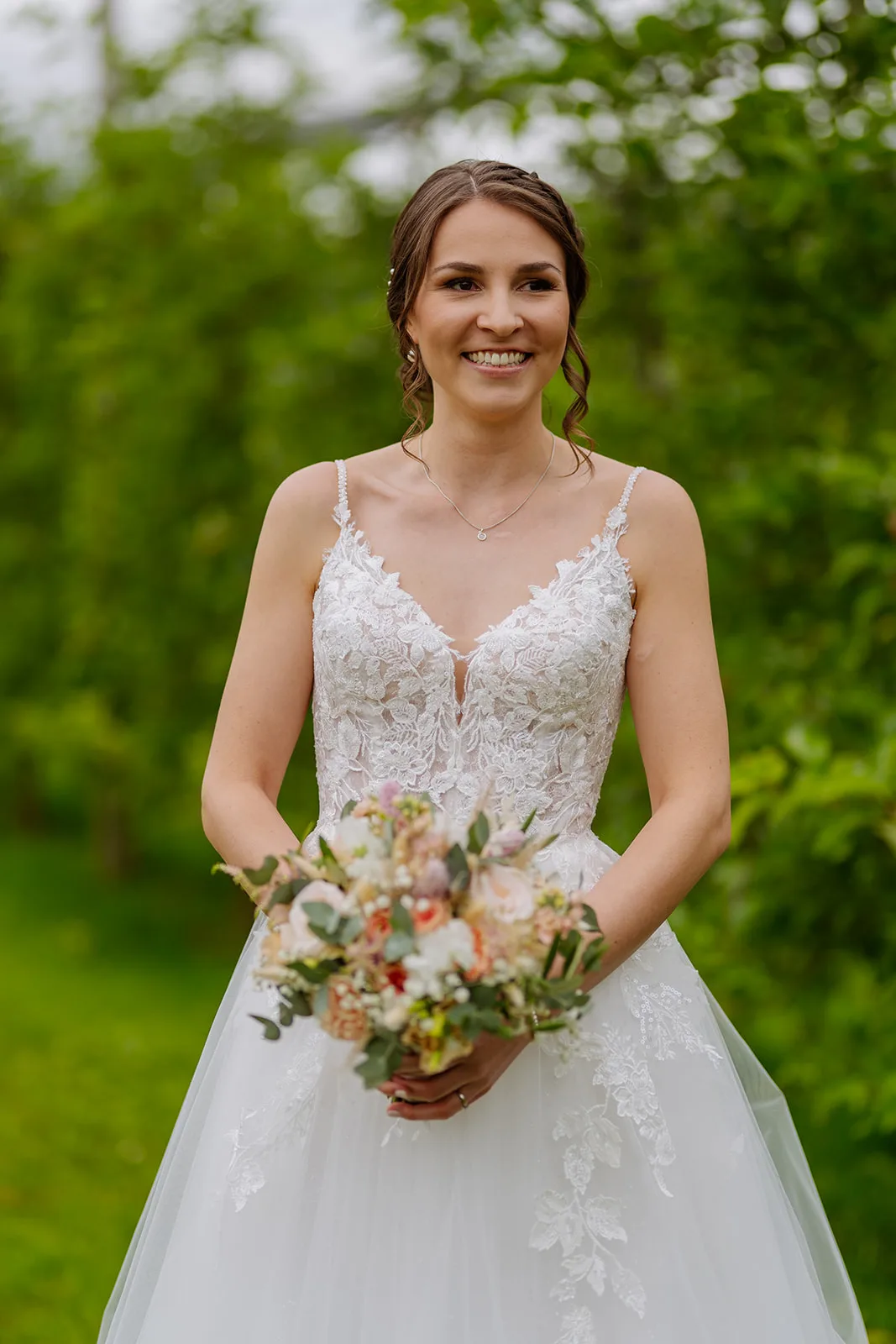 Braut im Spitzenkleid mit Brautstrauss im Obstgarten der Hochzeitslocation Bächlihof Jona