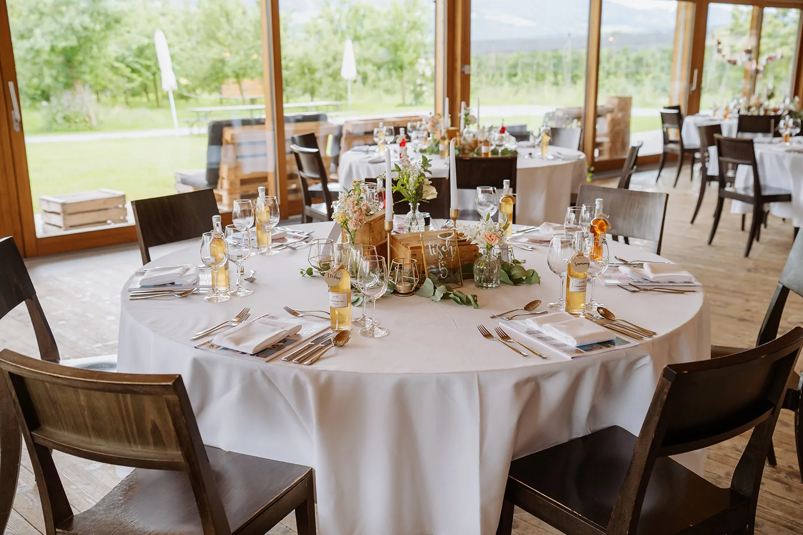 Rund gedeckter Hochzeitstisch mit Blick auf die Obstplantage im Festsaal des Bächlihofs in Jona